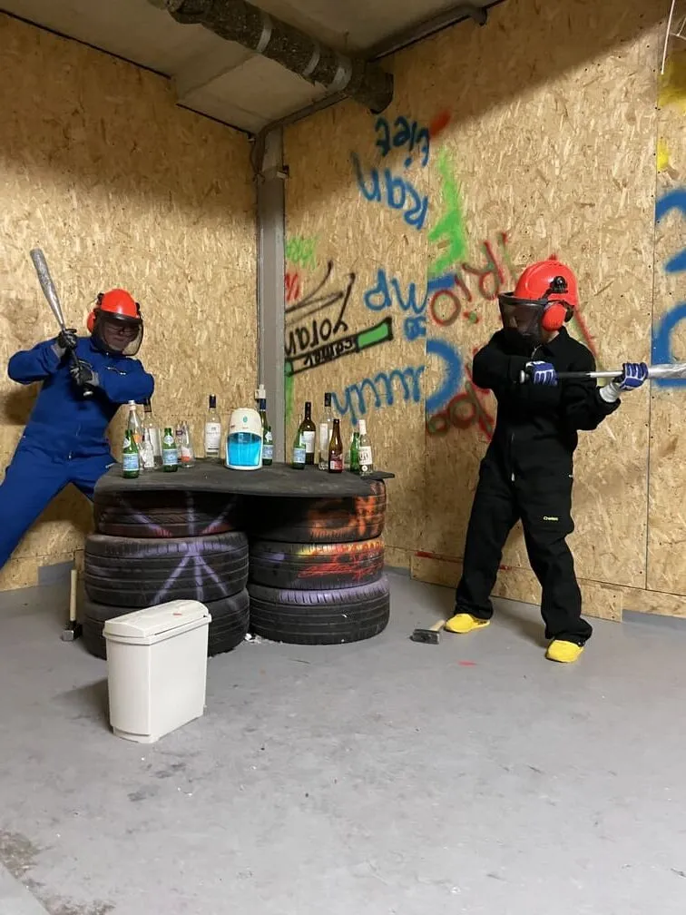 Rage room participants about to smash bottles on a table