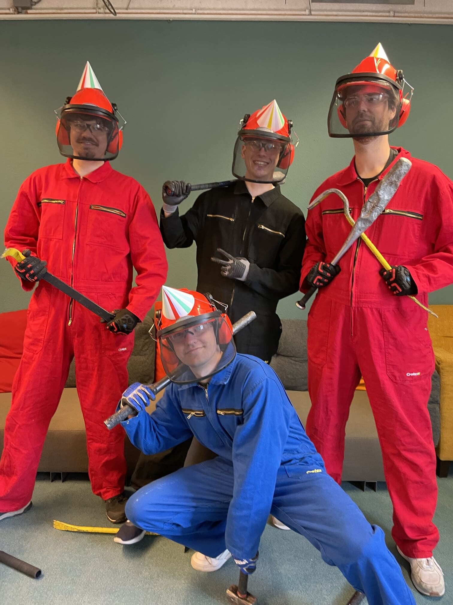 Friends in party hats and jumpsuits posing with crowbars at The Rage Room