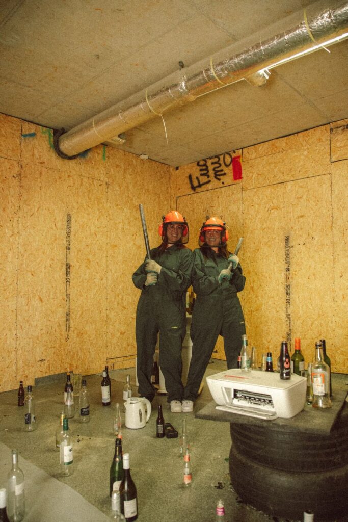 Two friends laughing and posing with sledgehammers after a rage room session